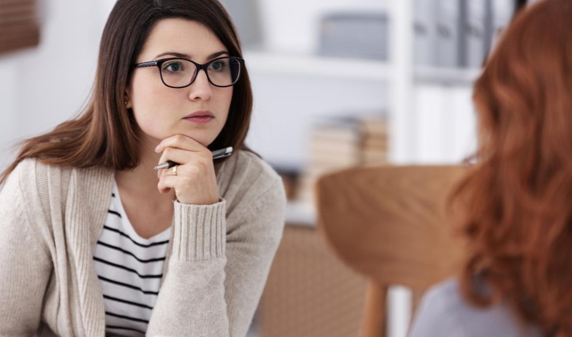 Junge Psychologin mit Brille im Gespräch mit einer Klientin