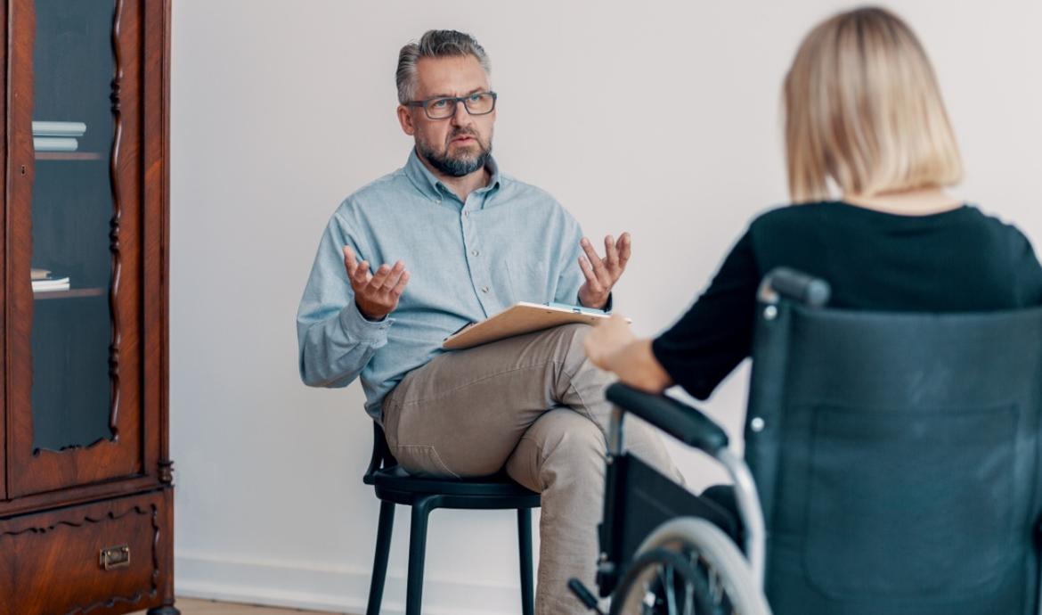 Berater im Gespräch mit Frau im Rollstuhl