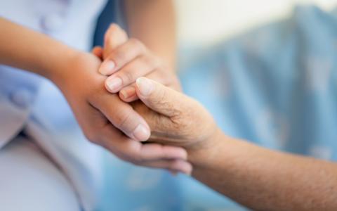 Pflegerin hält die Hand einer alten Frau