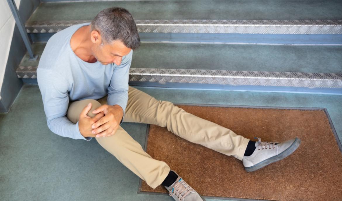 Mann hält sich nach Sturz von einer Treppe das schmerzende Knie